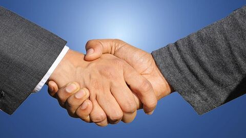 Bildausschnitt Handschlag, zu sehen sind zwei Hände mit dem Ansatz zweier Ärmel.