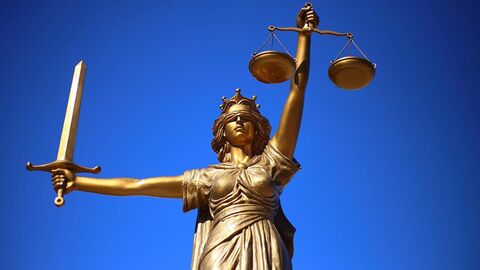 Justitia vor einem blauen Hintergrund.