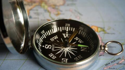 Aufgeklappter magnetischer Kompass liegt auf einer Landkarte.